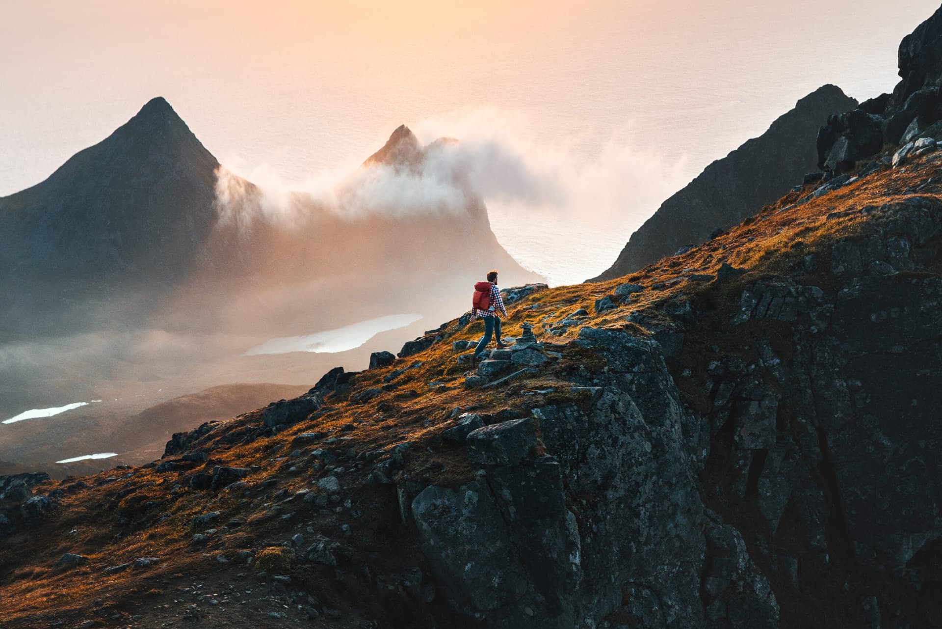 Man climbing mountains traveling in Norway tourist solo hiking in Lofoten islands outdoor traveler with backpack active healthy lifestyle adventure summer vacations